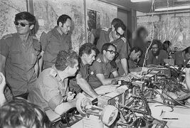 חדר פיקוד – פיקוד דרום "דְּבֵלָה" (ר"ת: חפ"ק פד"ם) בזמן מלחמת יום כיפור, אוקטובר 1973. במרכז מימין לשמאל: עומד האלוף רחבעם זאבי (גנדי) יושבים: ראשון מימין (מדבר בקשר) אל"ם שי תמרי (קצין אג"מ פיקוד דרום), אלוף פיקוד דרום אלוף שמואל גונן (גורודיש), הרמטכ"ל רא"ל דוד אלעזר, האלוף עזר ויצמן (עוזר הרמטכ"ל), מאחורי הרמטכ"ל דדו, עומד תא"ל אשר לוי (רמ"ט פיקוד דרום).